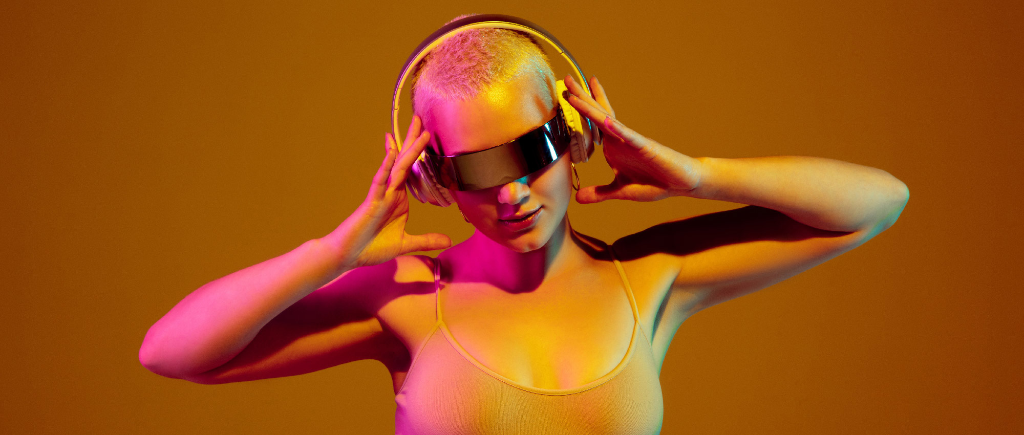 Junge Frau mit kurzen Haaren trägt futuristische VR-Brille und Kopfhörer, umgeben von buntem Licht.​​​​​​​​​​​​​​​​​​​​​​​​​​​​​​​​​​​​​​​​​​​​​​