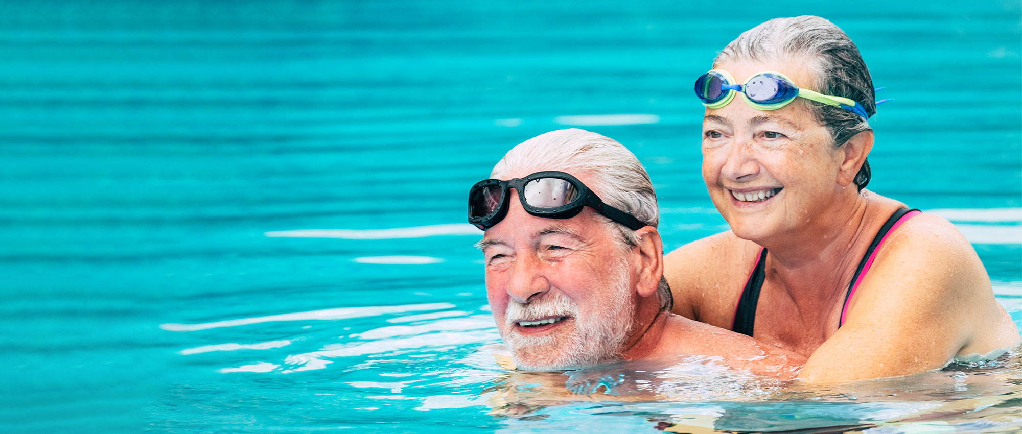 Älteres Paar mit Schwimmbrillen im Schwimmbad beim Schwimmen und Spaß haben im Wasser​​​​​​​​​​​​​​​​​​​​​​​​​​​​​​​​​​​​​​​​​​​​​​​​​​​​​​​​​​​​