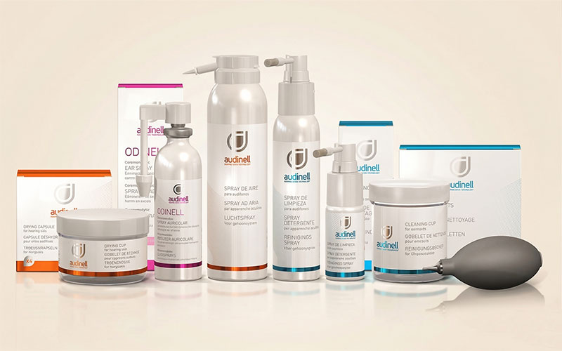 Audinell Pflegeprodukte für Hörgeräte: Reinigungssprays, Trockenkapseln und Reinigungsbecher auf hellem Hintergrund​​​​​​​​​​​​​​​​​​​​​​​​​​​​​​