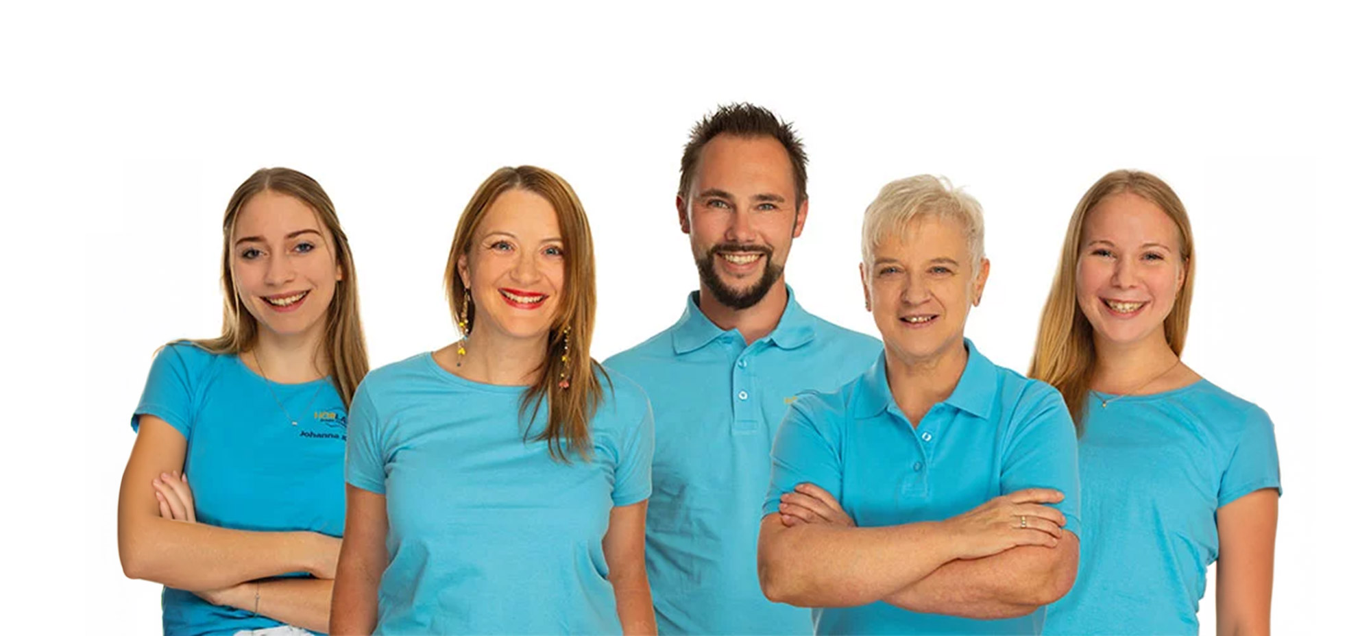 Fünf lächelnde Personen in blauen Shirts stehen vor weißem Hintergrund und wirken freundlich und offen.​​​​​​​​​​​​​​​​​​​​​​​​​​​​​​​​​​​​​​​​​​