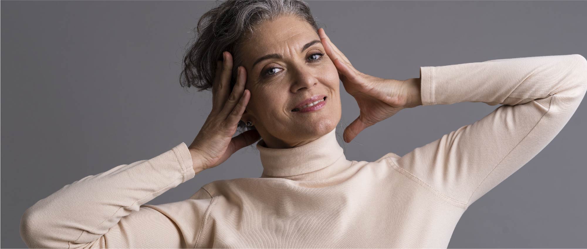 Porträt einer lächelnden Frau mit grauen Haaren in hellem Rollkragenpullover vor grauem Hintergrund​​​​​​​​​​​​​​​​​​​​​​​​​​​​​​​​​​​​​​​​​​​​​​