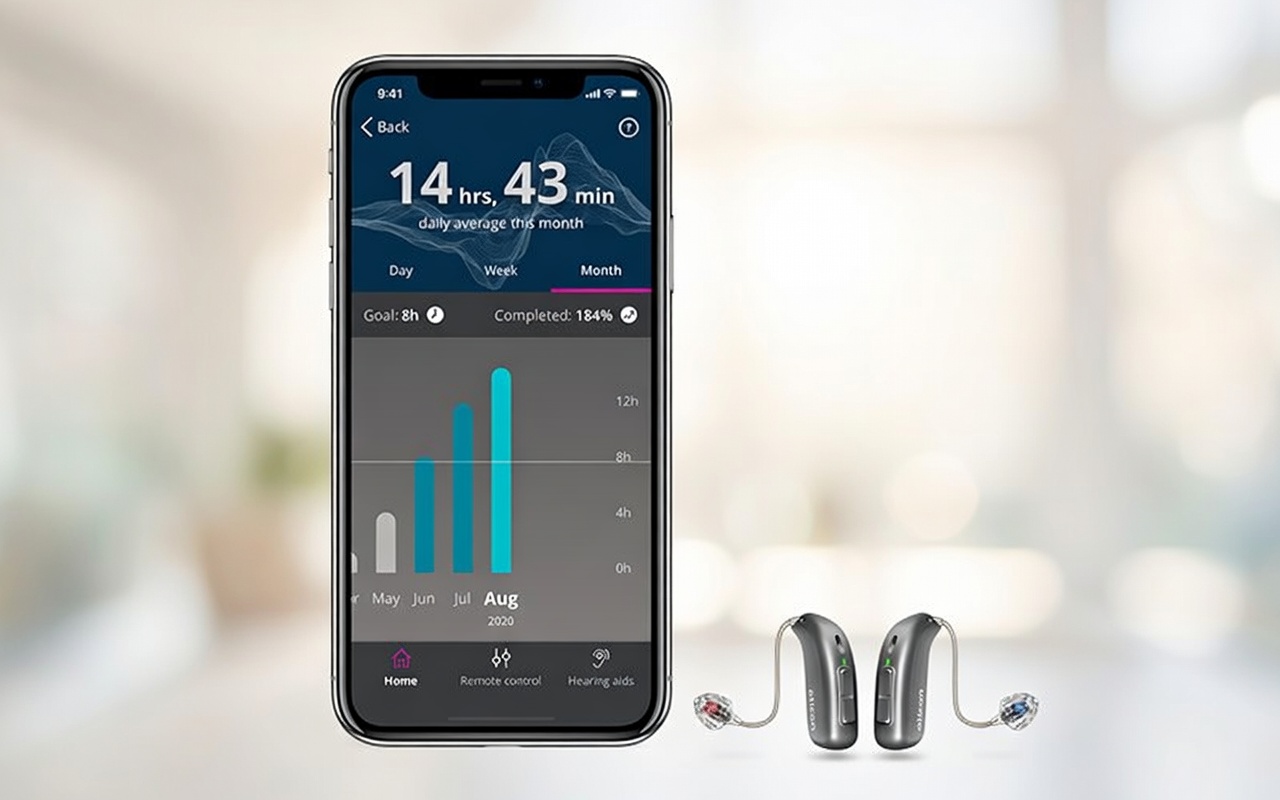 Smartphone zeigt Oticon App mit Hörzeit-Statistik, daneben zwei silberne Hörgeräte auf hellem Hintergrund​​​​​​​​​​​​​​​​​​​​​​​​​​​​​​​​​​​​​​​​