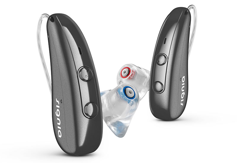 Zwei silberne Premium Hörgeräte mit farblich markierten transparenten Ohrpassstücken vor weißem Hintergrund​​​​​​​​​​​​​​​​​​​​​​​​​​​​​​​​​​​​​​