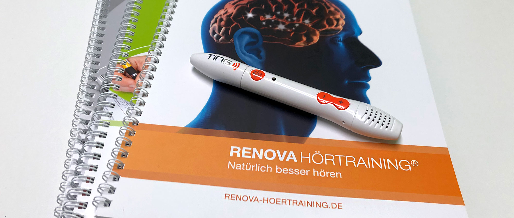 Mehrere spiralgebundene Renova Hörtraining Broschüren mit Stift und Gehirnillustration auf weißem Hintergrund​​​​​​​​​​​​​​​​​​​​​​​​​​​​​​​​​​​​