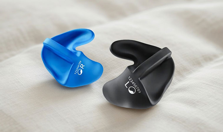 Zwei Schlafschutz Ohrstöpsel in Blau und Schwarz liegen auf hellem Stoff. Komfortable Passform für ruhigen Schlaf.​​​​​​​​​​​​​​​​​​​​​​​​​​​​​​​