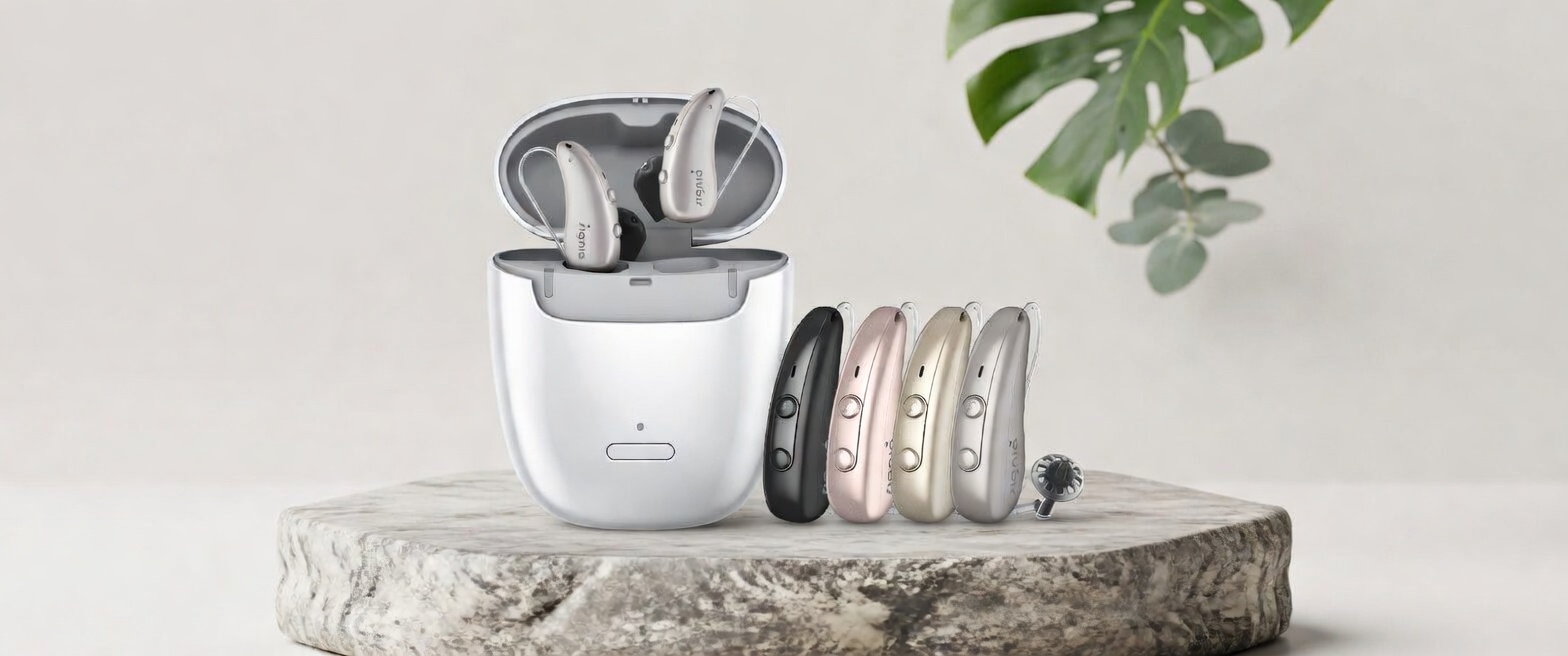 Signia Pure Charge&Go Hörgeräte in verschiedenen Farben mit Ladeetui auf Steinplatte vor neutralem Hintergrund​​​​​​​​​​​​​​​​​​​​​​​​​​​​​​​​​​​