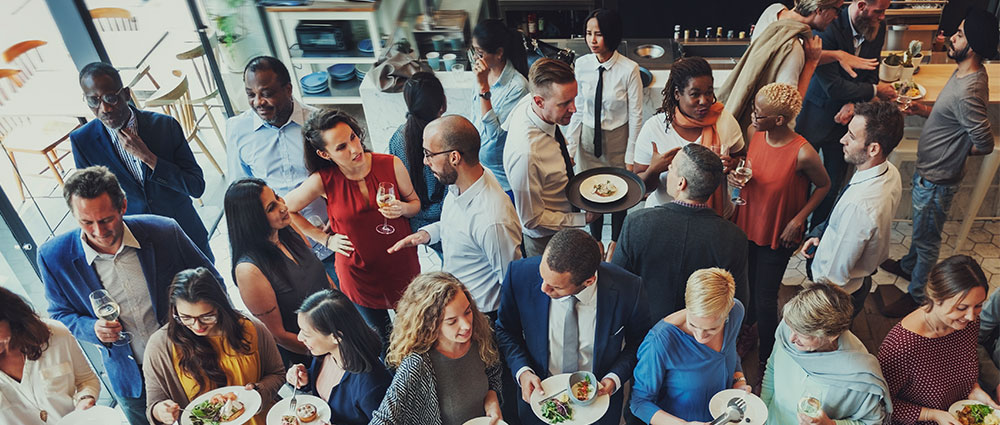 Vielfältige Gruppe von Menschen bei einem Empfang mit Speisen und Getränken in heller, moderner Umgebung​​​​​​​​​​​​​​​​​​​​​​​​​​​​​​​​​​​​​​​​​