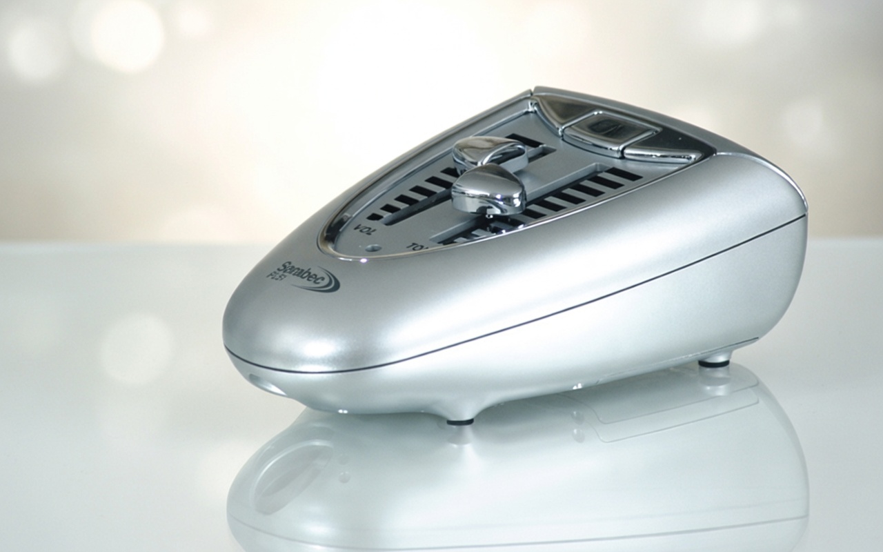 Moderner silberner Telefonverstärker mit Lautstärkeregler auf weißem, reflektierendem Untergrund in heller Umgebung​​​​​​​​​​​​​​​​​​​​​​​​​​​​​​