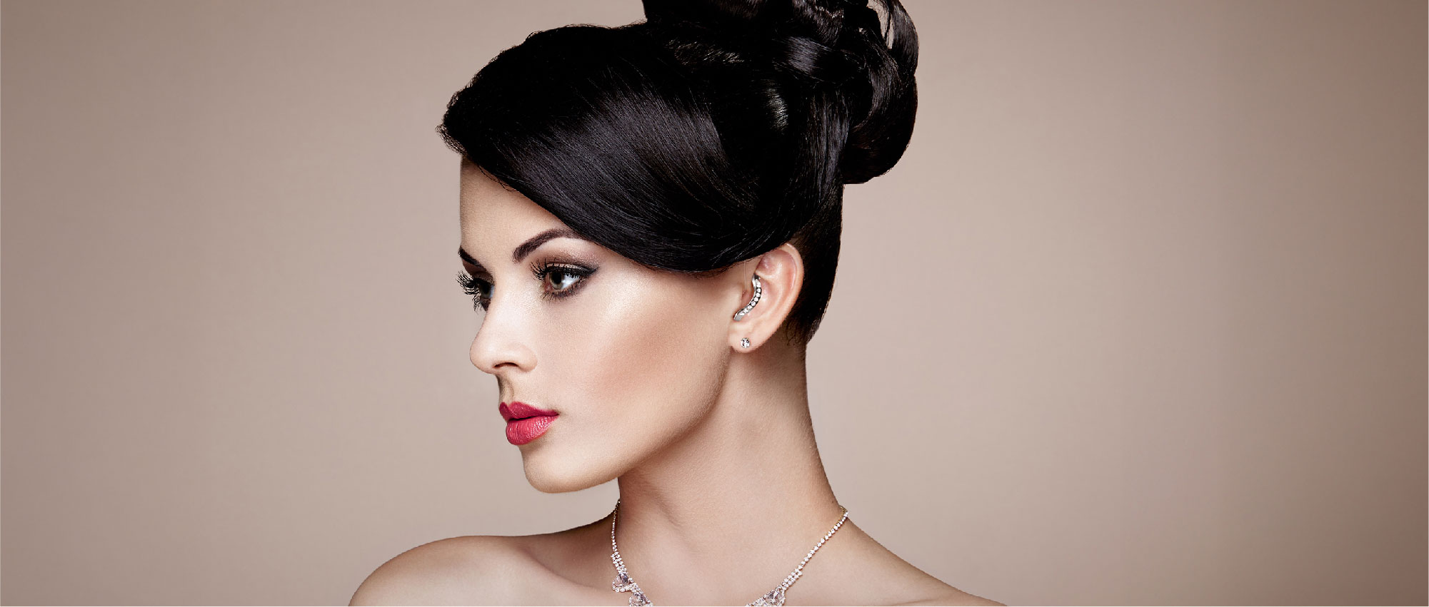 Porträt einer Frau mit Hochsteckfrisur, rotem Lippenstift und funkelndem Schmuck vor neutralem Hintergrund​​​​​​​​​​​​​​​​​​​​​​​​​​​​​​​​​​​​​​​