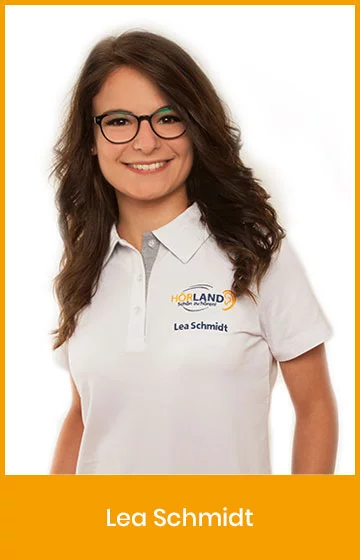 Lea Schmidt, Mitarbeiterin der Hörland Filiale, lächelt in die Kamera und trägt ein weißes Polo-Shirt mit Firmenlogo.