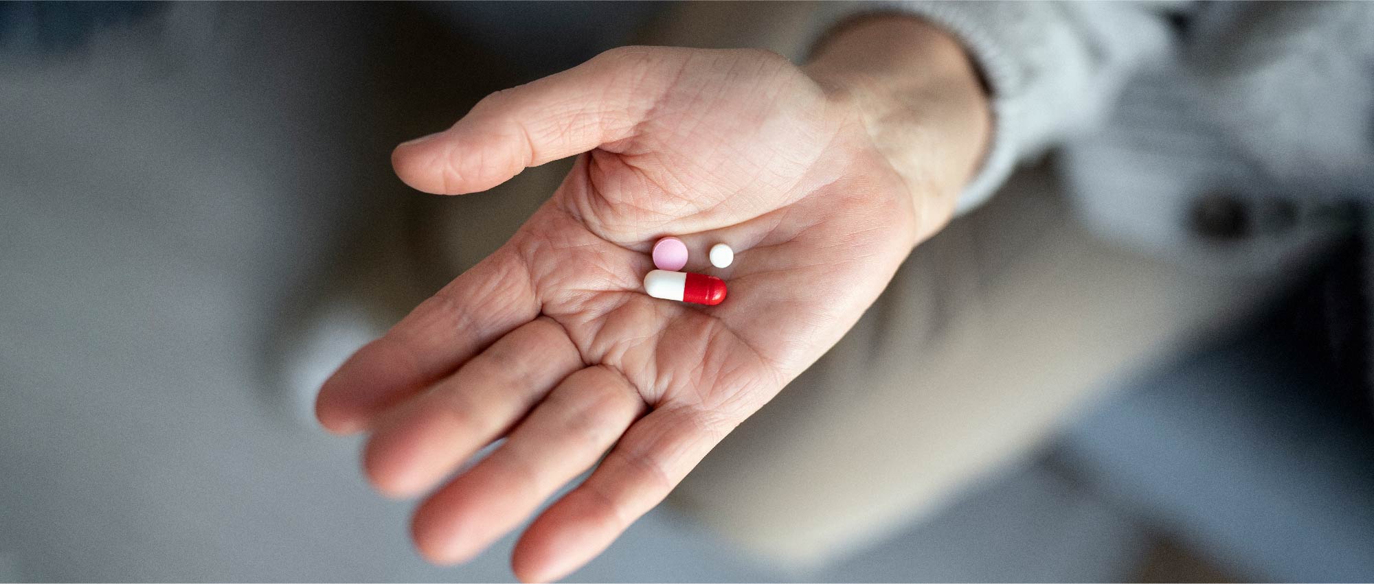 Eine Hand hält rote und weiße Tabletten. Einige Medikamente können das Gehör beeinträchtigen, was den Einsatz von Hörgeräten notwendig machen kann. Eine Hand hält rote und weiße Tabletten. Einige Medikamente können das Gehör beeinträchtigen, was den Einsatz von Hörgeräten notwendig machen kann.