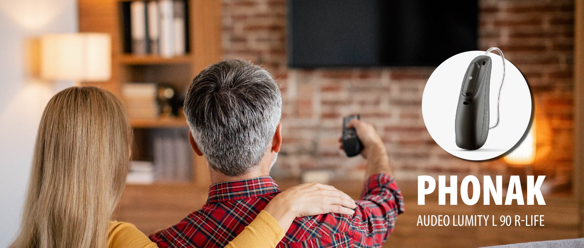 Ein Paar sitzt gemeinsam auf dem Sofa und schaut fern, während ein Phonak Hörgerät gezeigt wird. Moderne Hörgeräte mit Bluetooth ermöglichen drahtloses Audio-Streaming. Ein Paar sitzt gemeinsam auf dem Sofa und schaut fern, während ein Phonak Hörgerät gezeigt wird. Moderne Hörgeräte mit Bluetooth ermöglichen drahtloses Audio-Streaming.