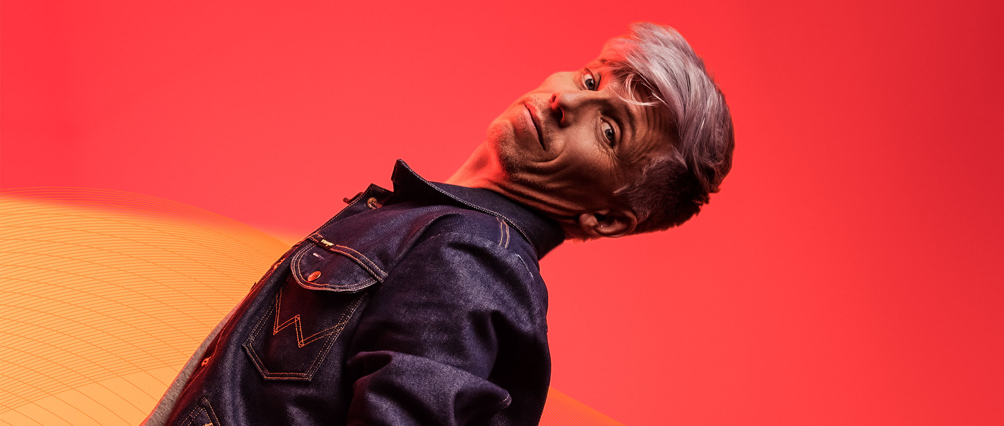 Mann posiert vor einem roten Hintergrund und trägt ein Im-Ohr-Hörgerät. Moderne Hörgerätetechnologie für klare Klangqualität und Stil. Mann posiert vor einem roten Hintergrund und trägt ein Im-Ohr-Hörgerät. Moderne Hörgerätetechnologie für klare Klangqualität und Stil.