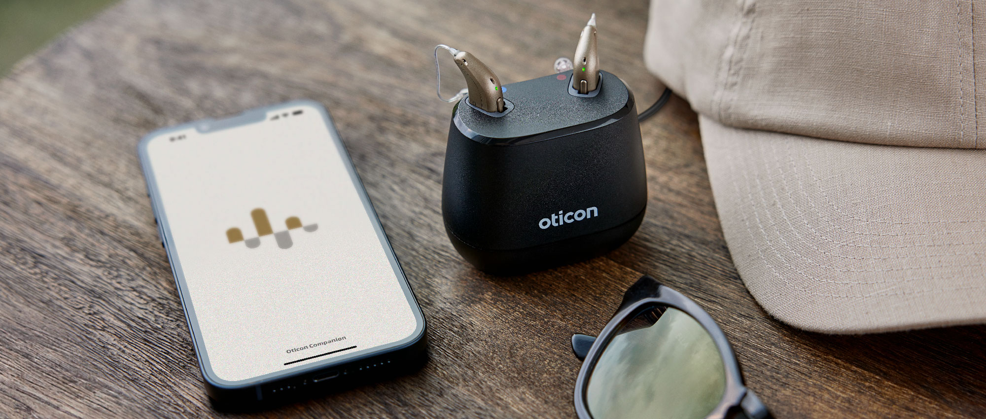 Oticon Hörgeräte in der Ladestation neben einem Smartphone mit der Oticon Companion App. Die Oticon Intent Hörgeräte bieten innovative Geräuschsensoren und nahtloses Bluetooth-Streaming für ein verbessertes Hörerlebnis. Oticon Hörgeräte in der Ladestation neben einem Smartphone mit der Oticon Companion App. Die Oticon Intent Hörgeräte bieten innovative Geräuschsensoren und nahtloses Bluetooth-Streaming für ein verbessertes Hörerlebnis.